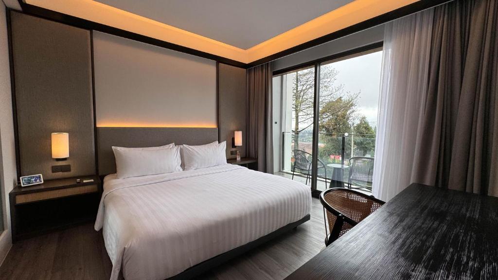 een hotelkamer met een bed en een groot raam bij Grand ASTON Puncak Hotel & Resort in Puncak