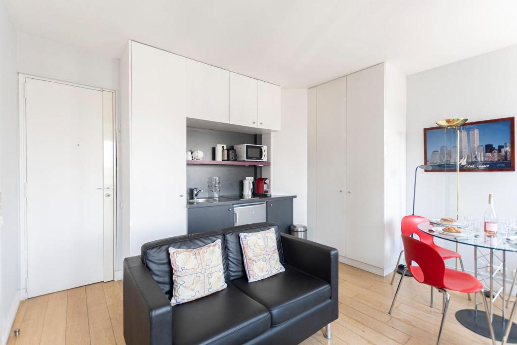 un salon avec un canapé noir et une table dans l'établissement GuestReady -Cozy Apartment with Eiffel Tower view, à Paris