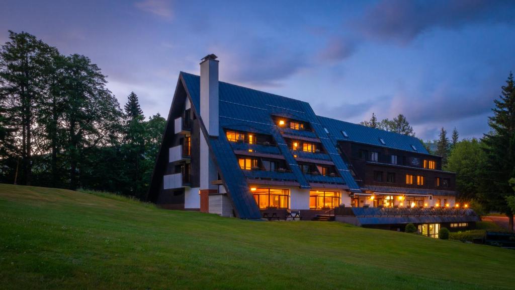 a building on a hill with its lights on at Wellness Hotel Šedý Vlk in Harrachov