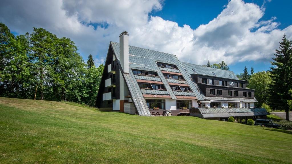 a large building on a hill with a green field at Wellness Hotel Šedý Vlk in Harrachov