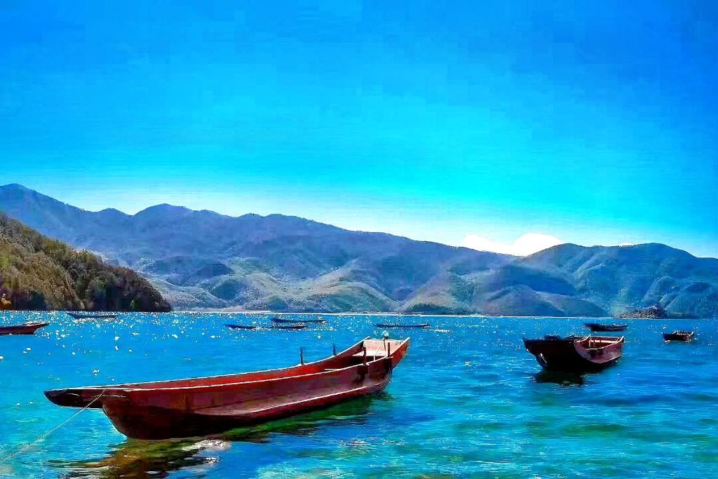 three boats sitting in a large body of water at 原乡文苑客栈 in Lijiang