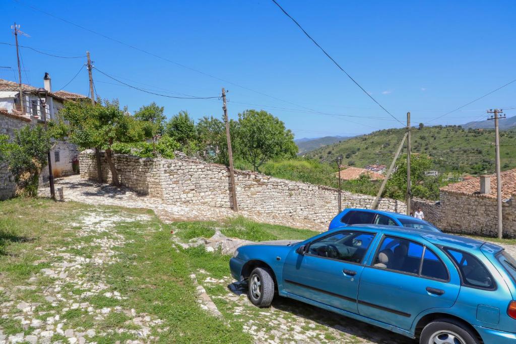 a blue car parked next to a stone wall at Guest House Vasili in Berat