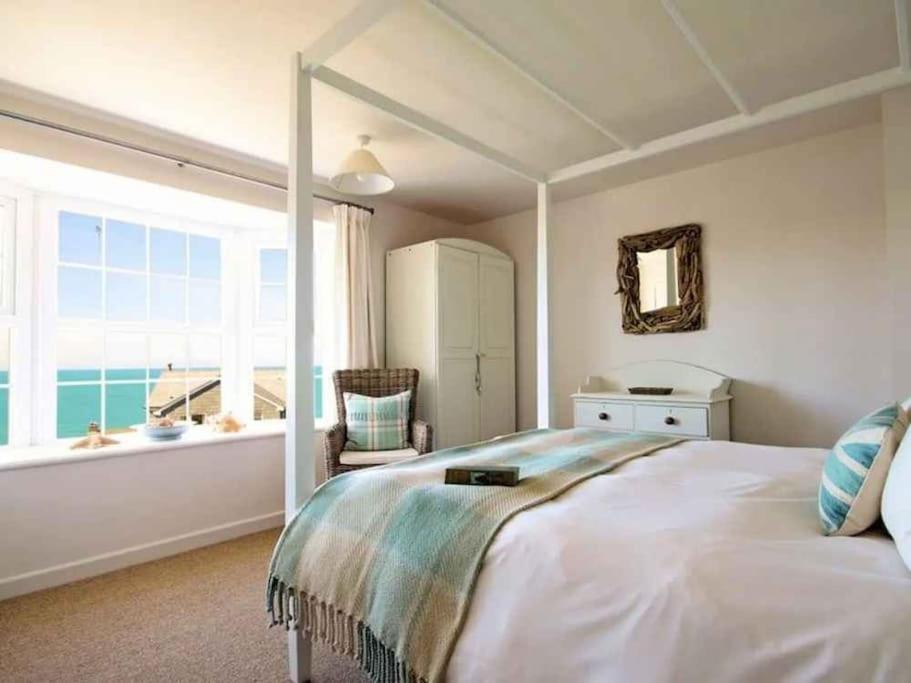 a bedroom with a large bed and a large window at Castaway, Port Isaac Bay Holidays in Port Isaac