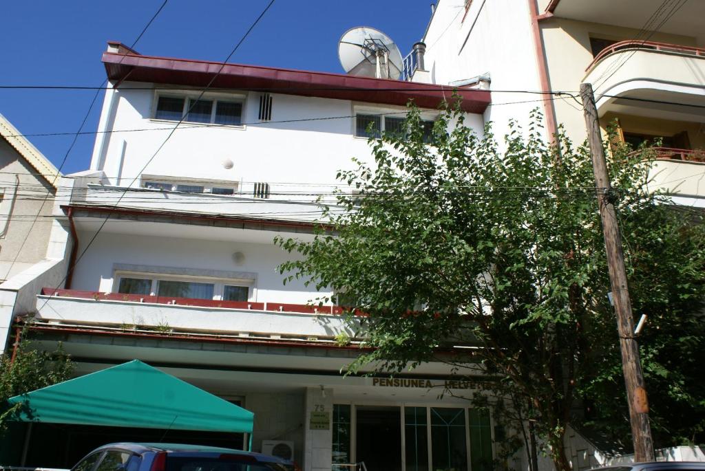 a white building with a green tent in front of it at Pensiunea Helvetia in Bucharest