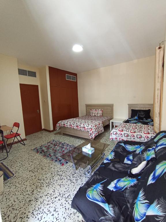 a room with two beds and a couch and a table at Sarker in Abu Dhabi