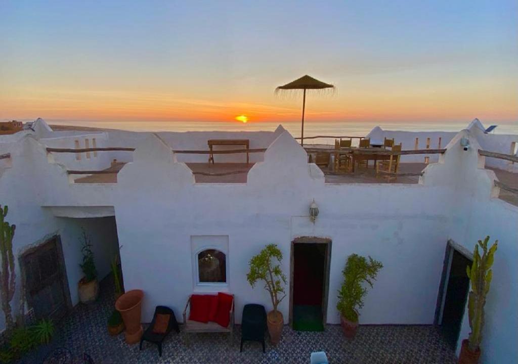 een wit gebouw met een zonsondergang op de achtergrond bij Riad Sahara Sunset Beach Agadir in Douaïra