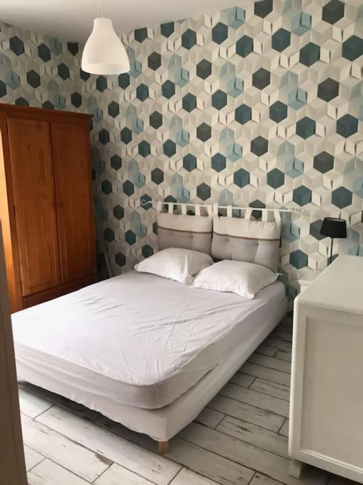 un lit dans une chambre avec un mur avec des coeurs dans l'établissement Berck-plage appartement, à Berck-sur-Mer