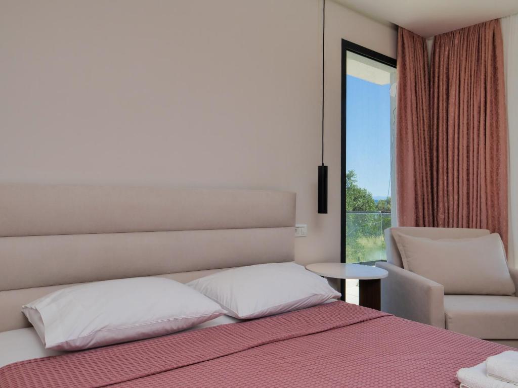 a bedroom with a bed and a chair and a window at Villa Tonia in Himare