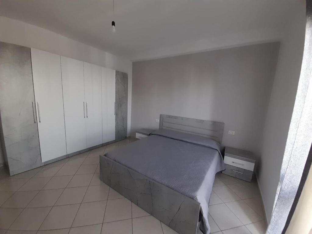 a bedroom with a large bed and white cabinets at Elezi House in Durrës