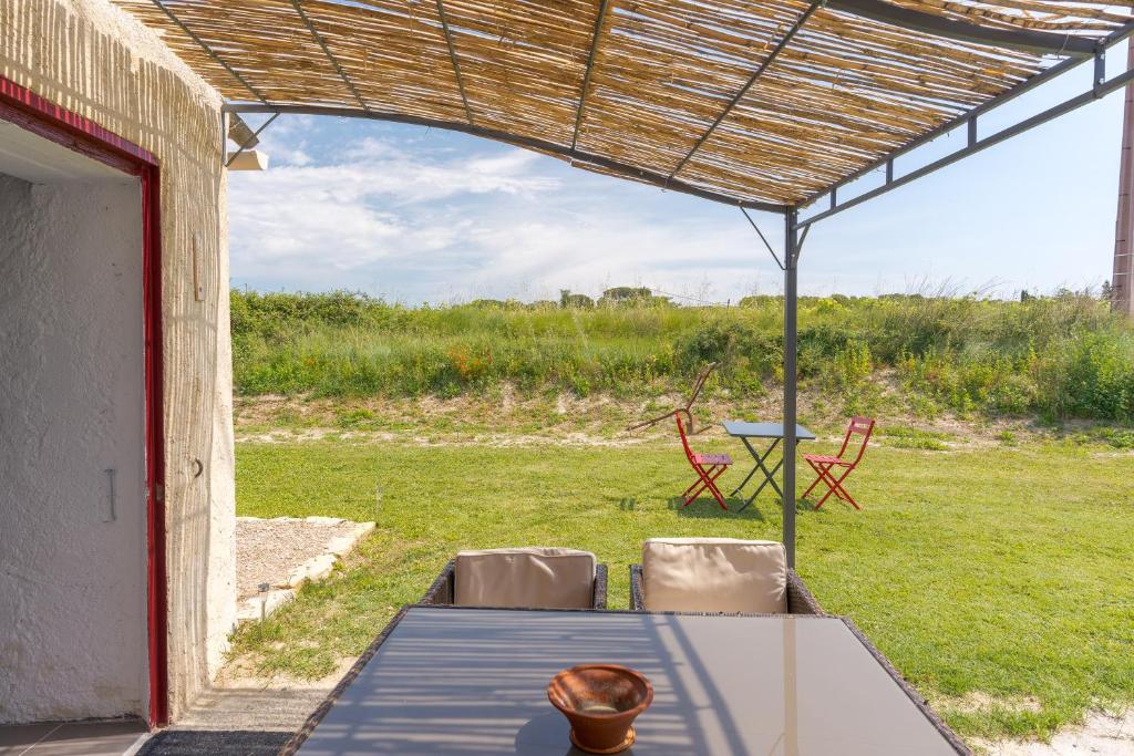 un patio avec une table et des chaises sous un toit dans l'établissement Cabanon en pleine nature, à La Tour-dʼAigues