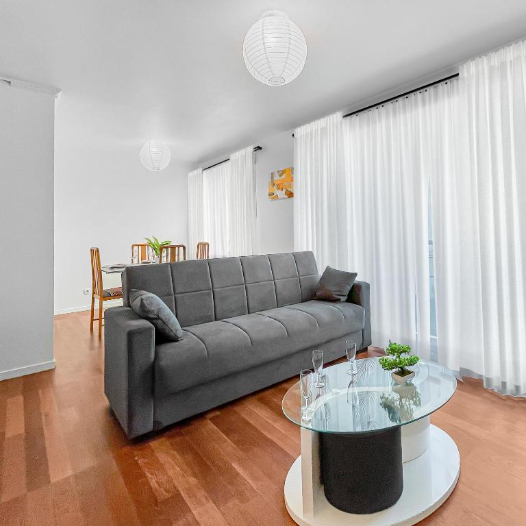 un salon avec un canapé et une table en verre dans l'établissement Escale Villa Pauline CDG, Villepinte Expo, Disney, à Villepinte