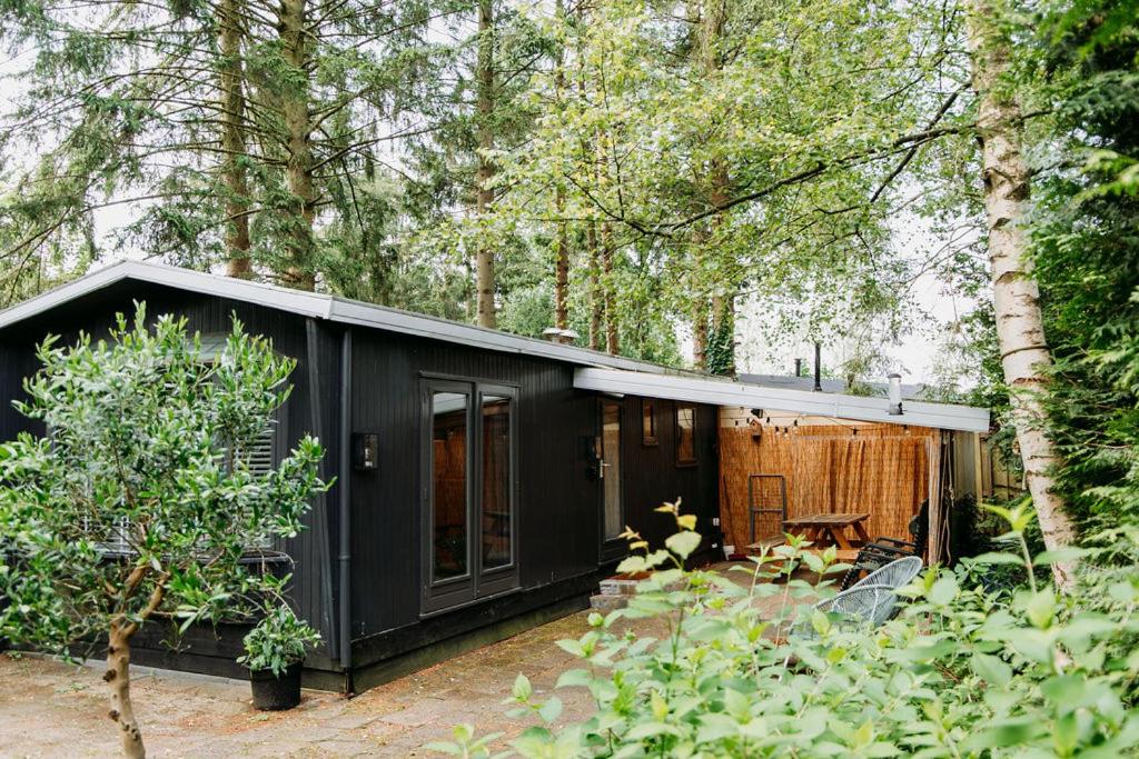 a black house in the middle of a forest at Tiny Cabin Mae op de Veluwe in Putten