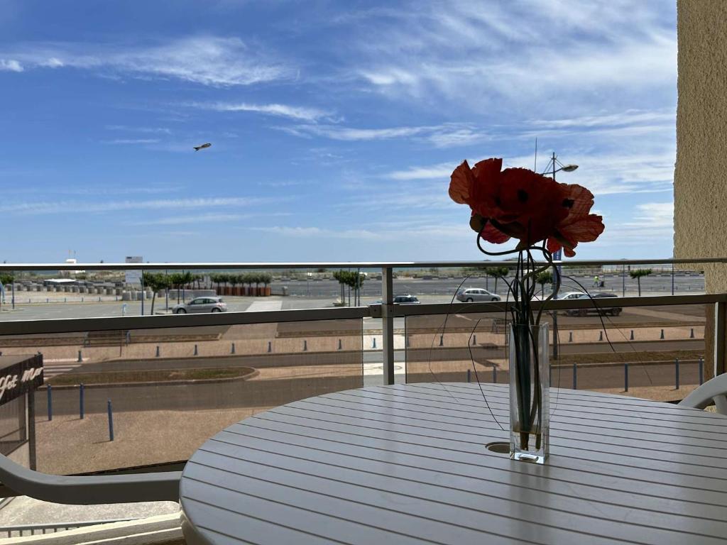 un vase de fleurs posé sur une table sur un balcon dans l'établissement Studio bord de mer, parking, animaux admis - FR-1-229D-226, à Saint Pierre La Mer