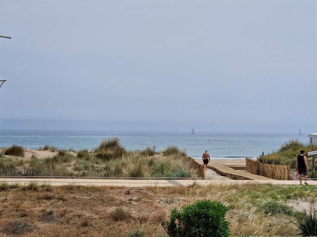 2 personnes marchant sur un sentier près de la plage dans l'établissement Appartement à 2 pas de la plage avec terrasse et parking - FR-1-387-150, à Marseillan