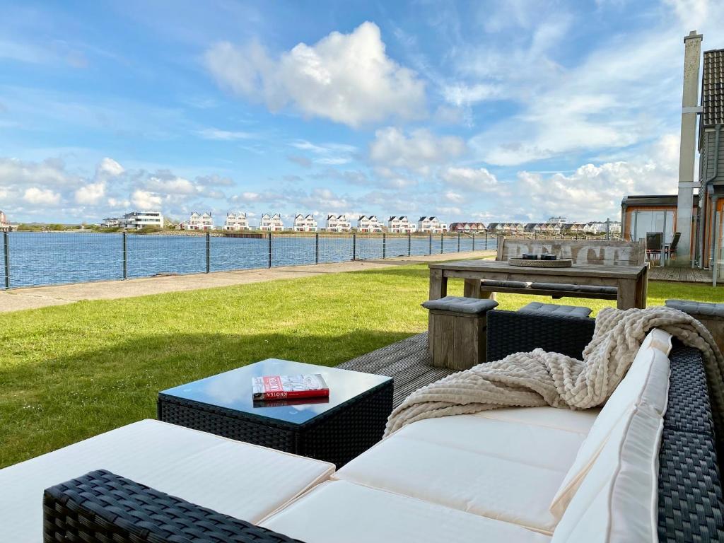 a patio with a couch and a table and the water at Ferienwohnung Pier 21 Olpenitz in Olpenitz