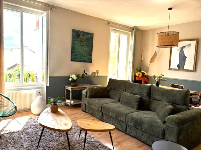 - un salon avec un canapé vert, des tables et des fenêtres dans l'établissement GRAND APPARTEMENT DE CARACTERE à VICHY, à Vichy