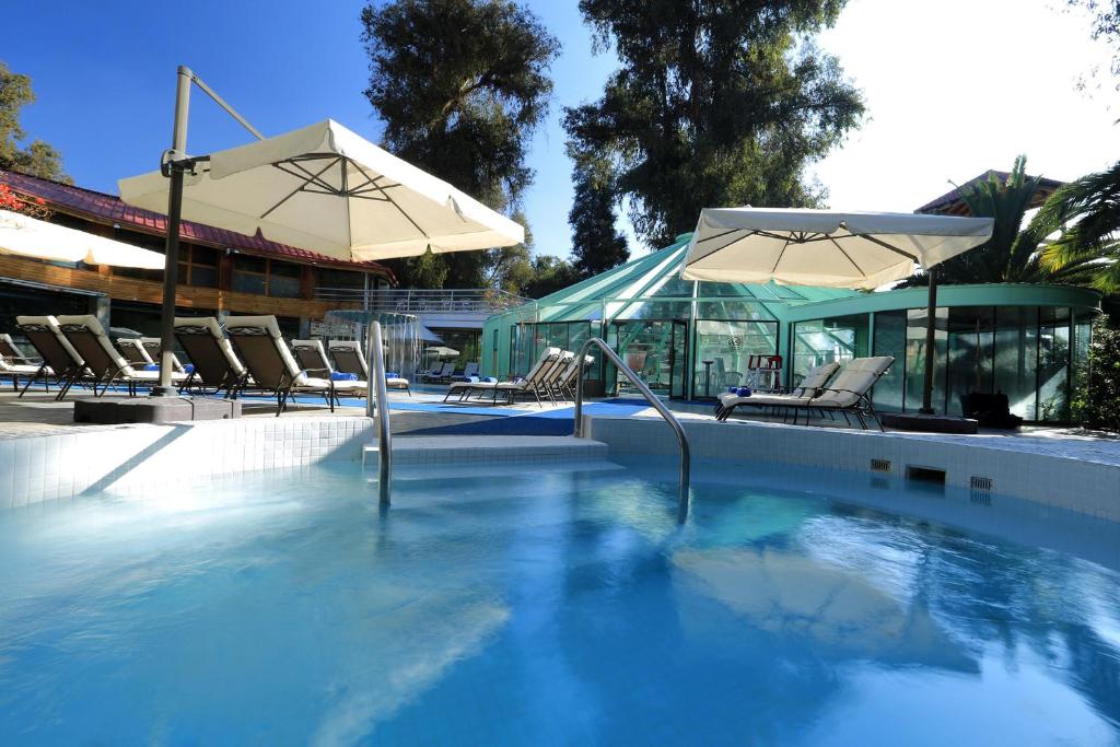 a swimming pool with two umbrellas and chairs at Termas El Corazon in San Esteban