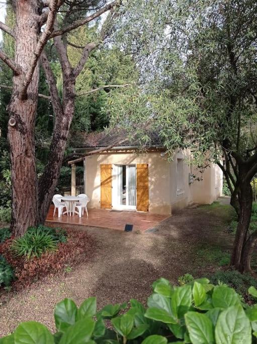 une maison avec une table et des chaises dans une cour dans l'établissement Petite maison dans un écrin de verdure, aux Angles (Gard)