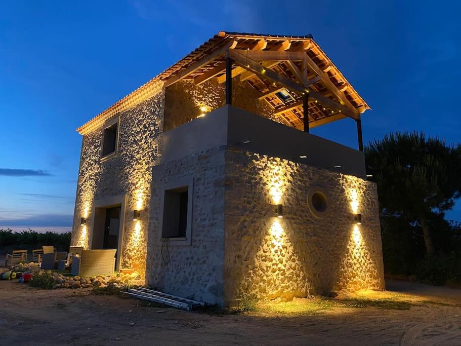 une maison en pierre avec des lumières sur son côté dans l'établissement Grange au milieu des vignes, à Béziers