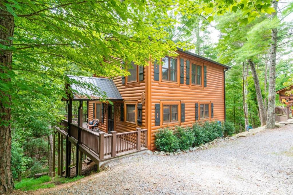 a log cabin in the woods with a driveway at Hibernation Station - Hot Tub, Fireplace, Serene Forest Views - Cherry Log, GA in Blue Ridge