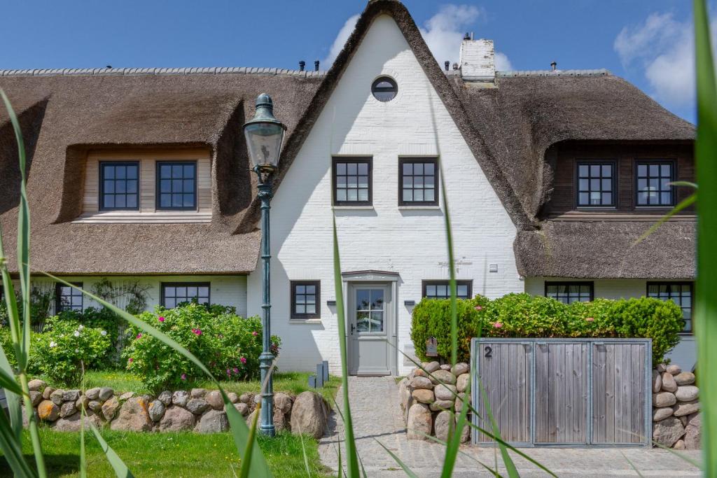 a white house with a thatched roof at Reethüs Syltliebe in Morsum