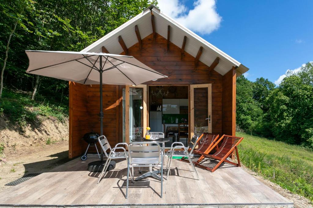 a wooden deck with a table and chairs and an umbrella at Chalet Pondok Indah in Plouégat-Moysan