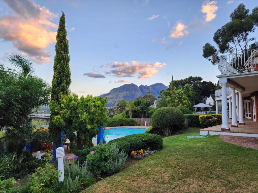 a garden with a pool and mountains in the background at Innisfree Manor in Somerset West