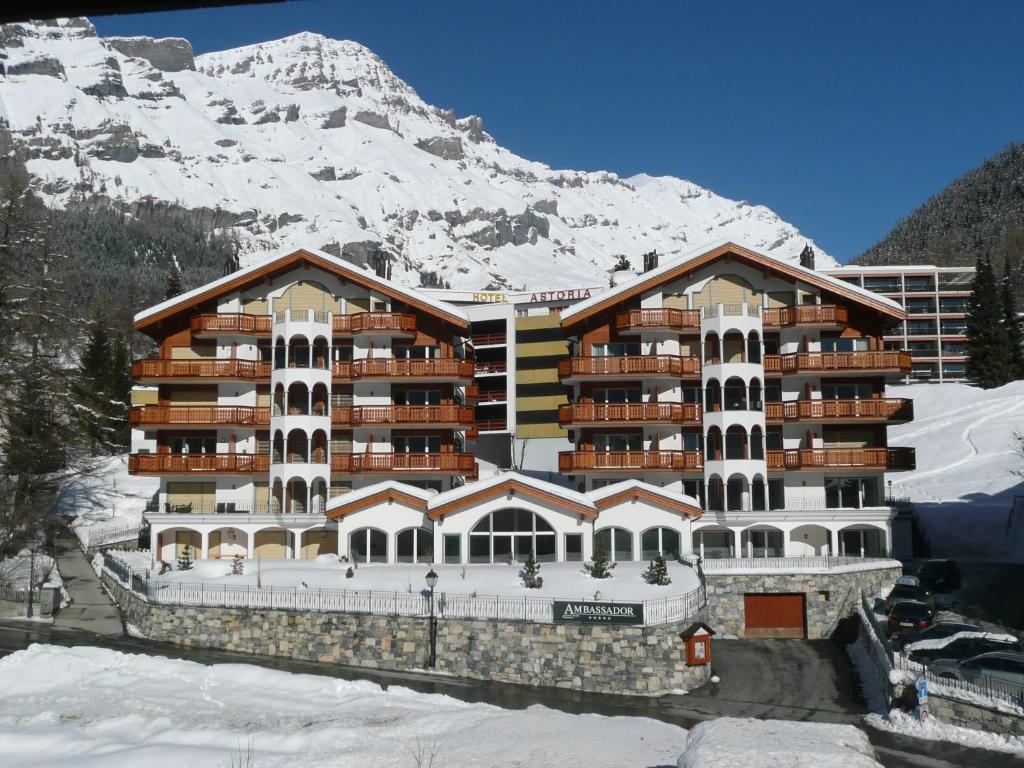 a large building with a snow covered mountain behind it at Residenz Ambassador B22 in Leukerbad