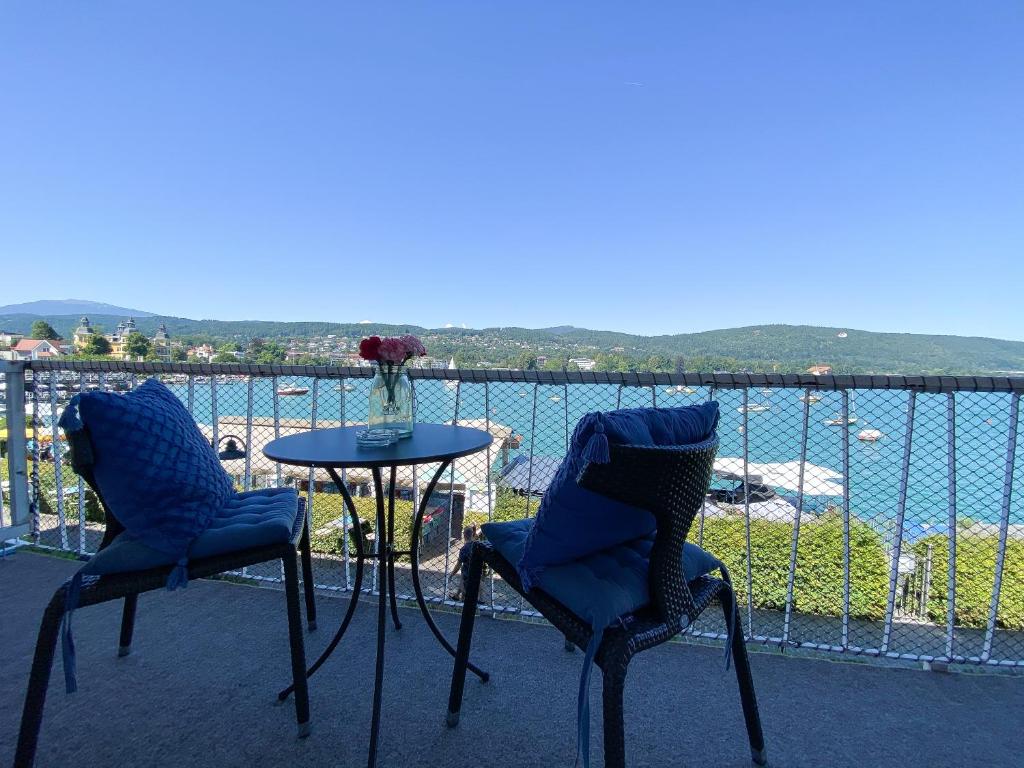 two chairs and a table on a balcony overlooking the water at Haus Zinnauer in Velden am Wörthersee