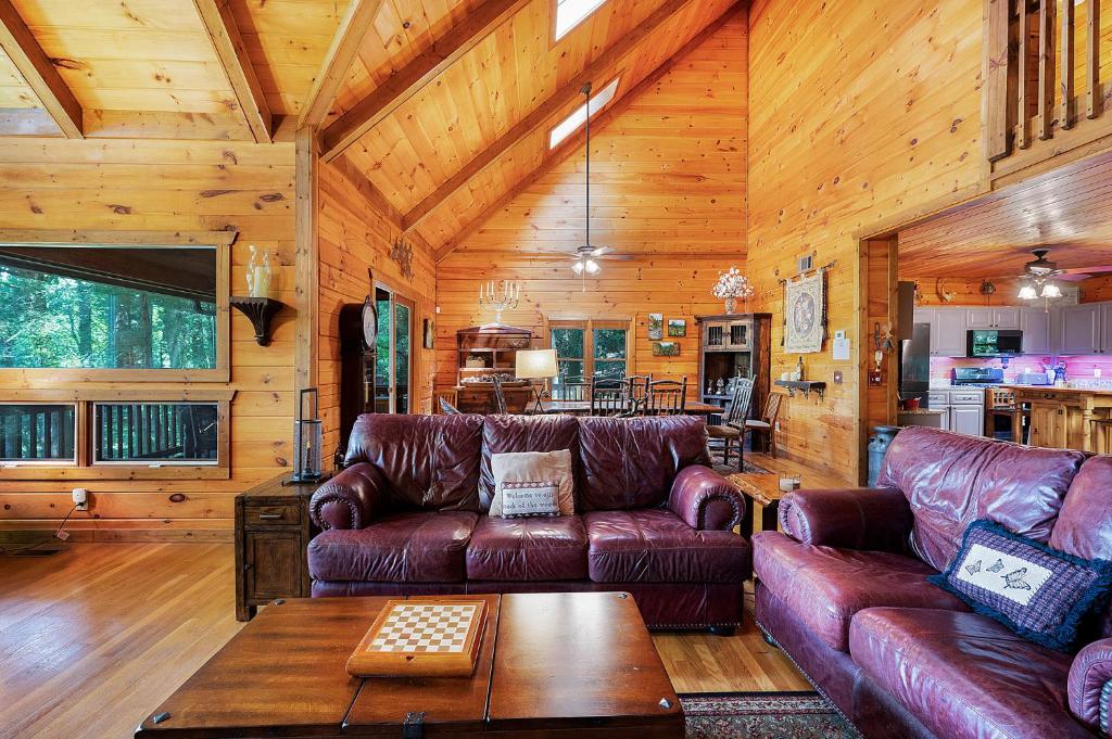a living room with leather couches and a table at Hazy Hideaway with View of Ellijay River in the North GA Mountains in Cherry Log