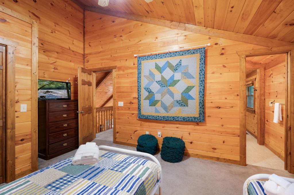 a log cabin bedroom with a bed and a quilt on the wall at Hazy Hideaway with View of Ellijay River in the North GA Mountains in Cherry Log