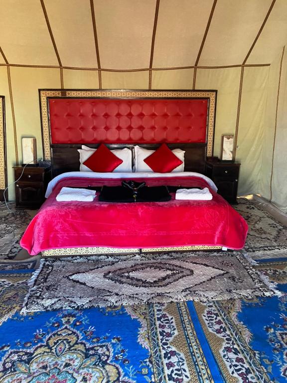 a large bed with a red headboard in a room at Luxury Local Camp in Merzouga
