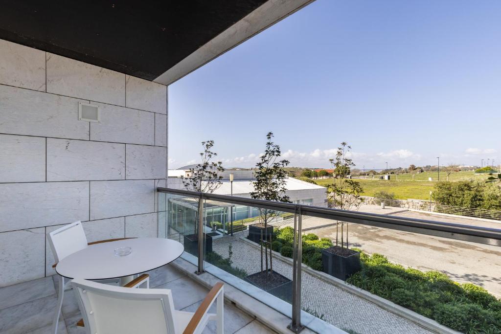a balcony with a table and chairs and a view at Crowne Plaza - Caparica Lisbon in Costa da Caparica