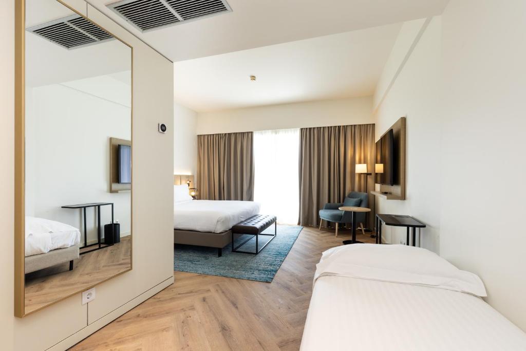 a hotel room with two beds and a mirror at Crowne Plaza - Caparica Lisbon in Costa da Caparica