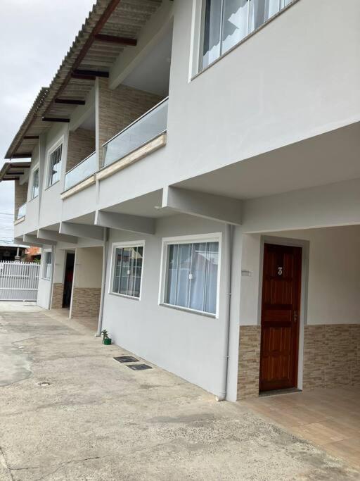 a white building with a brown door on it at Geminado da mada casa 3 in Penha