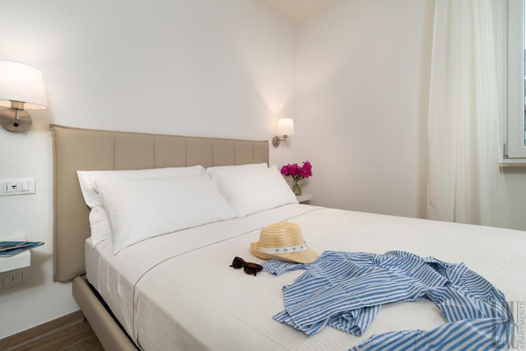 een bed met een hoed en kleren erop bij Belle Maison - Du Lac Apartments in Sirmione