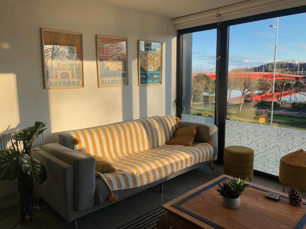 un salon avec un canapé et une grande fenêtre dans l'établissement Appartement centre ville avec vue sur l'Adour, à Bayonne