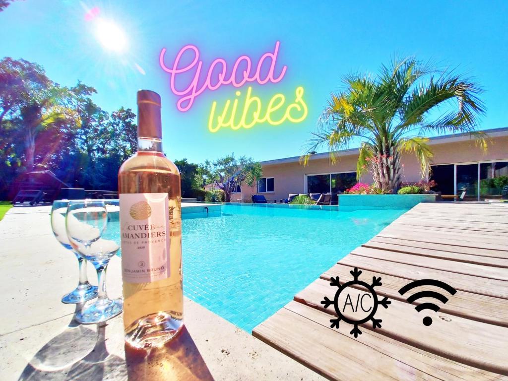 - une bouteille de vin et des verres à côté de la piscine dans l'établissement Elegante Villa-Piscine-Pétanque-Tout confort, à Fréjus