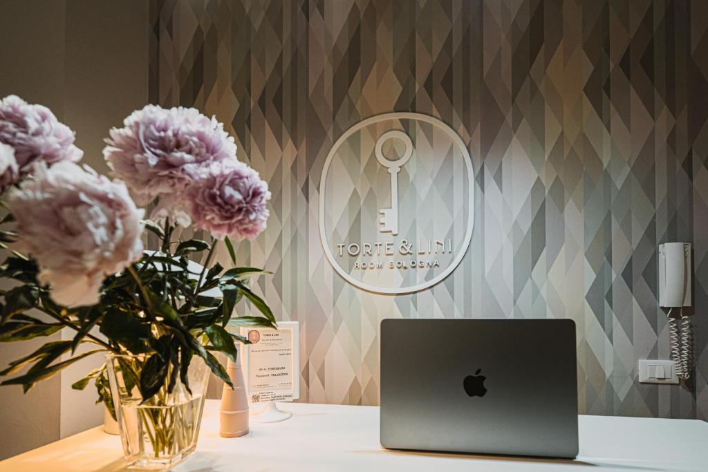 a table with a laptop computer and flowers on it at TORTE & LINI in Bologna