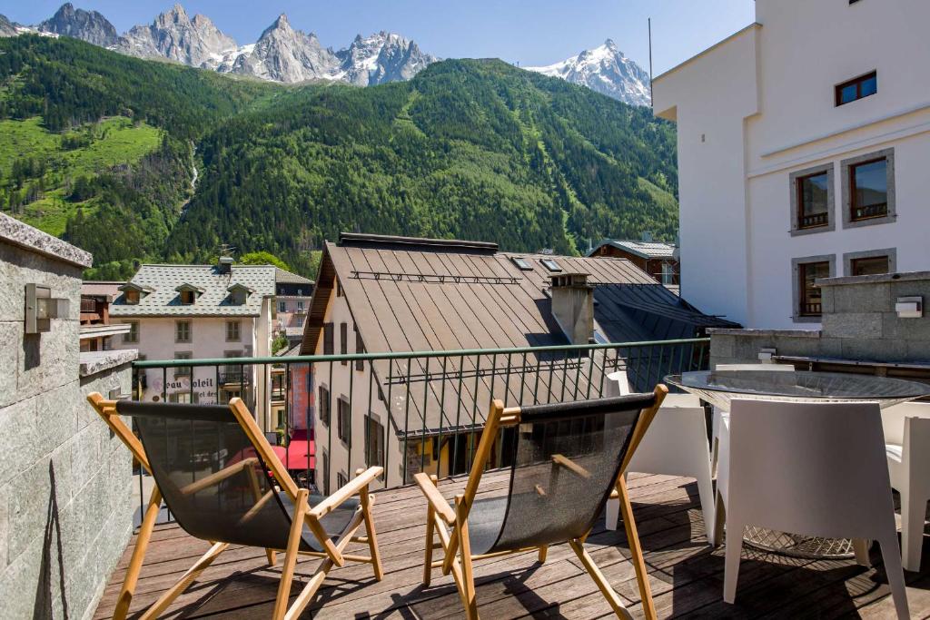 a balcony with two chairs and a table and mountains at Le Bartavel Apartment - Chamonix All Year in Chamonix-Mont-Blanc