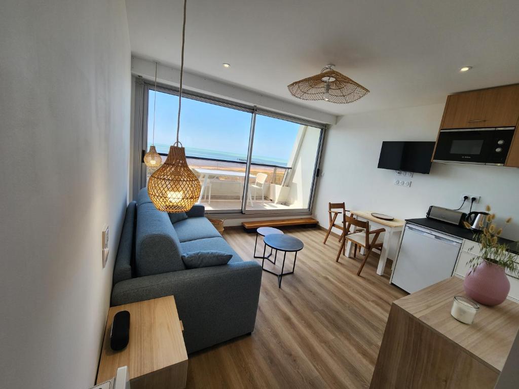 un salon avec un canapé bleu et une cuisine dans l'établissement Studio Face Mer, à Saint-Jean-de-Monts