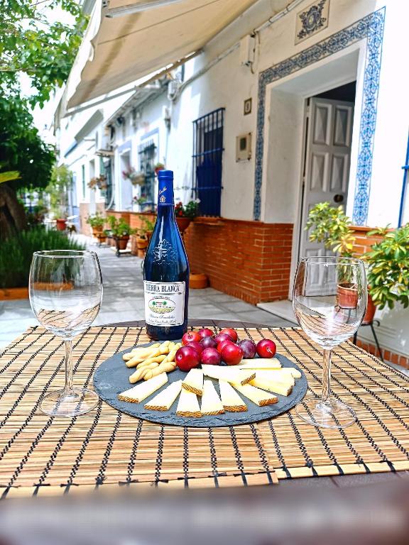 塞维利亚Típico y pintoresco patio de vecinos, con encanto的桌子上放有一瓶葡萄酒和奶酪,配以酒杯