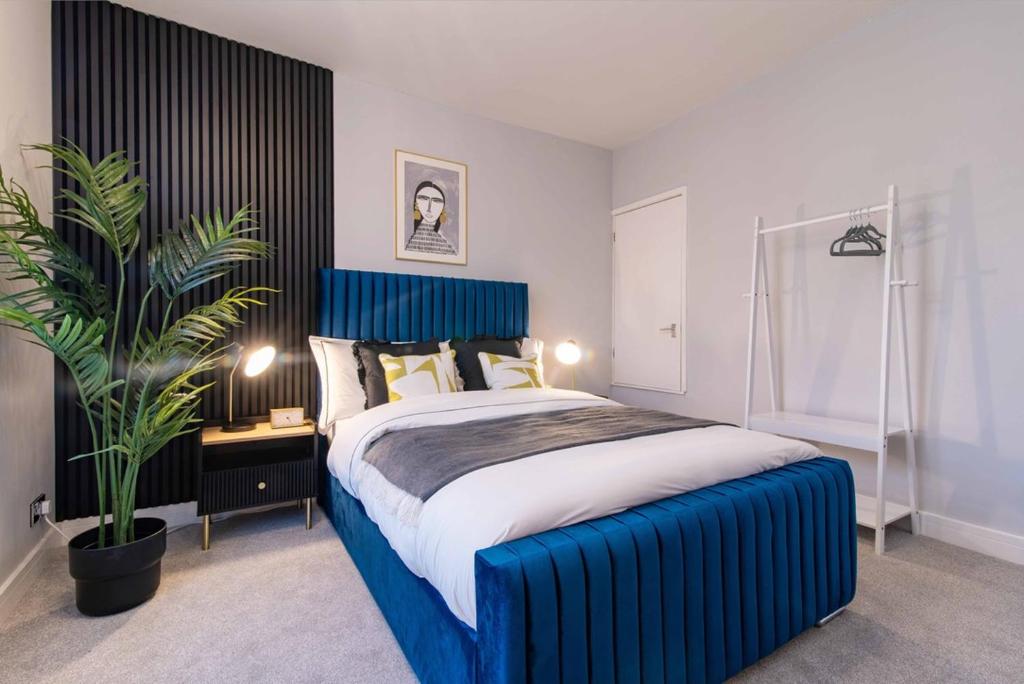a bedroom with a blue bed and a potted plant at Glasswing Stays Margaret st, central Sheffield in Sheffield