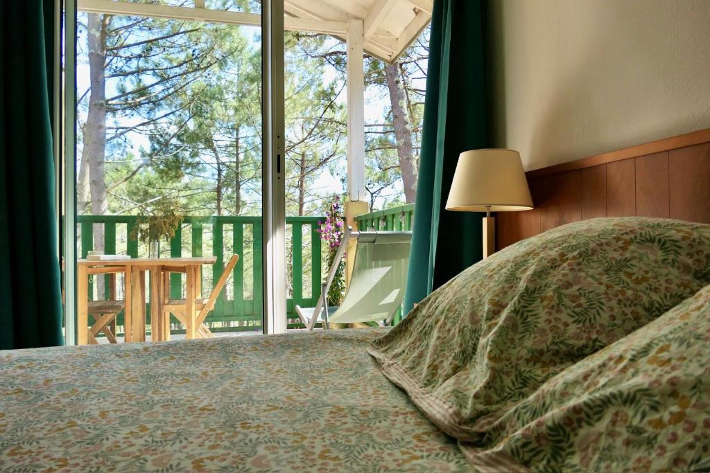 - une chambre avec un lit et une vue sur une terrasse couverte dans l'établissement Apt Les Grands Pins, entre Forêt, Lac et Océan, à Carcans