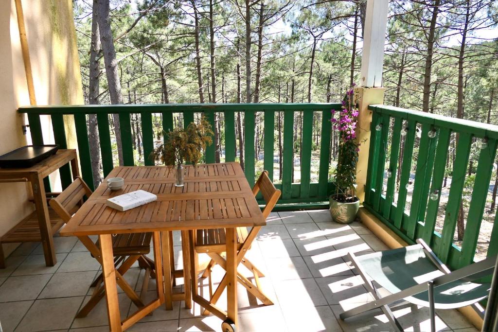 a wooden table and chairs on a balcony at Apt Les Grands Pins, entre Forêt, Lac et Océan in Carcans