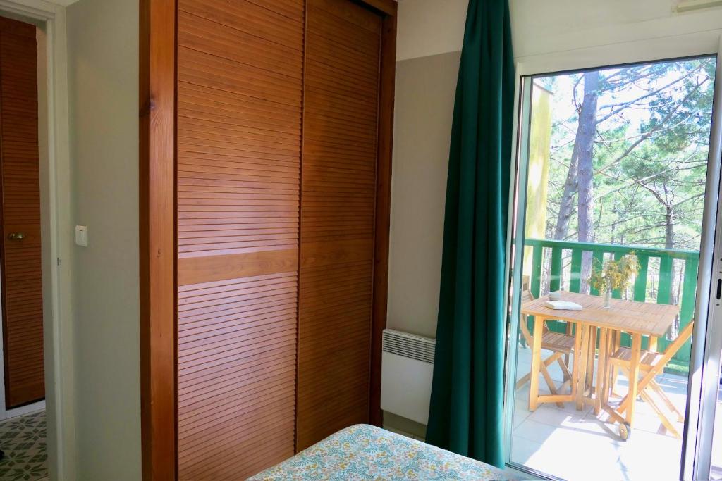 a room with a door to a balcony with a table at Apt Les Grands Pins, entre Forêt, Lac et Océan in Carcans
