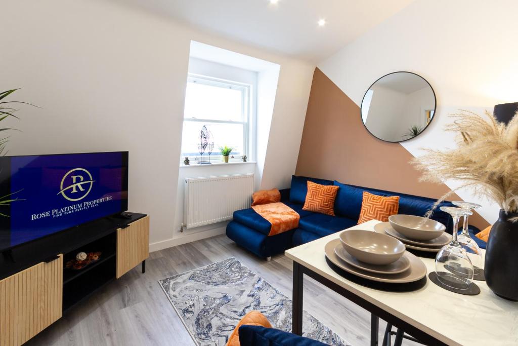 a living room with a blue couch and a tv at The Lanes Luxury - Rose Platinum Properties in Brighton & Hove