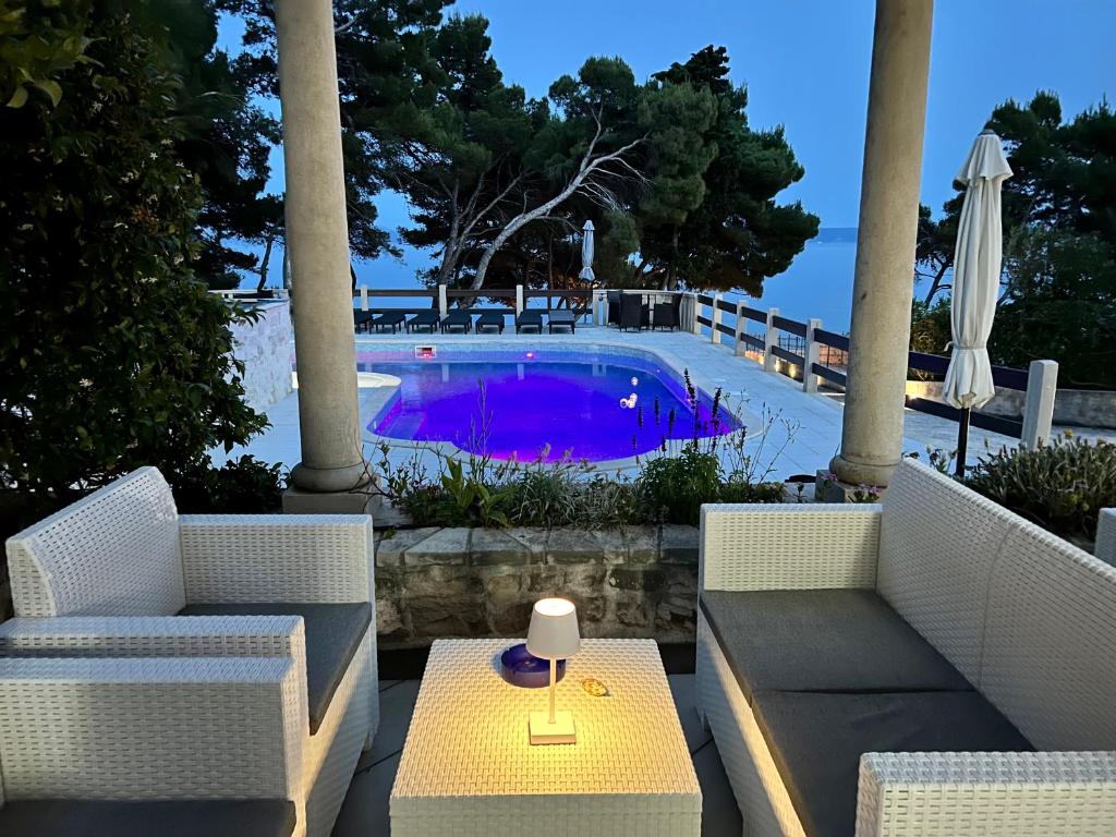 a patio with two chairs and a table and a pool at Vila Vera Seafront Apartments in Sumartin