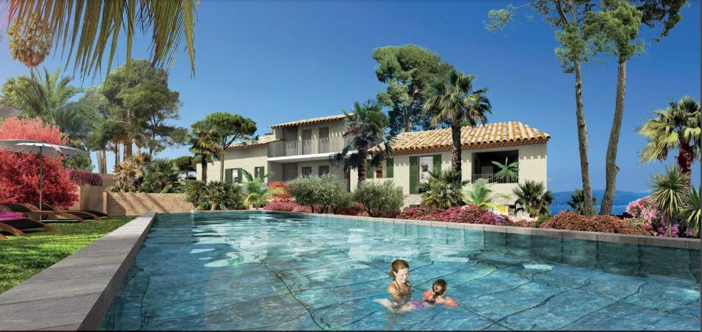 deux enfants nageant dans une piscine devant une maison dans l'établissement Superbe appart neuf centre ville 6 personnes calme avec jardin, à Sainte-Maxime