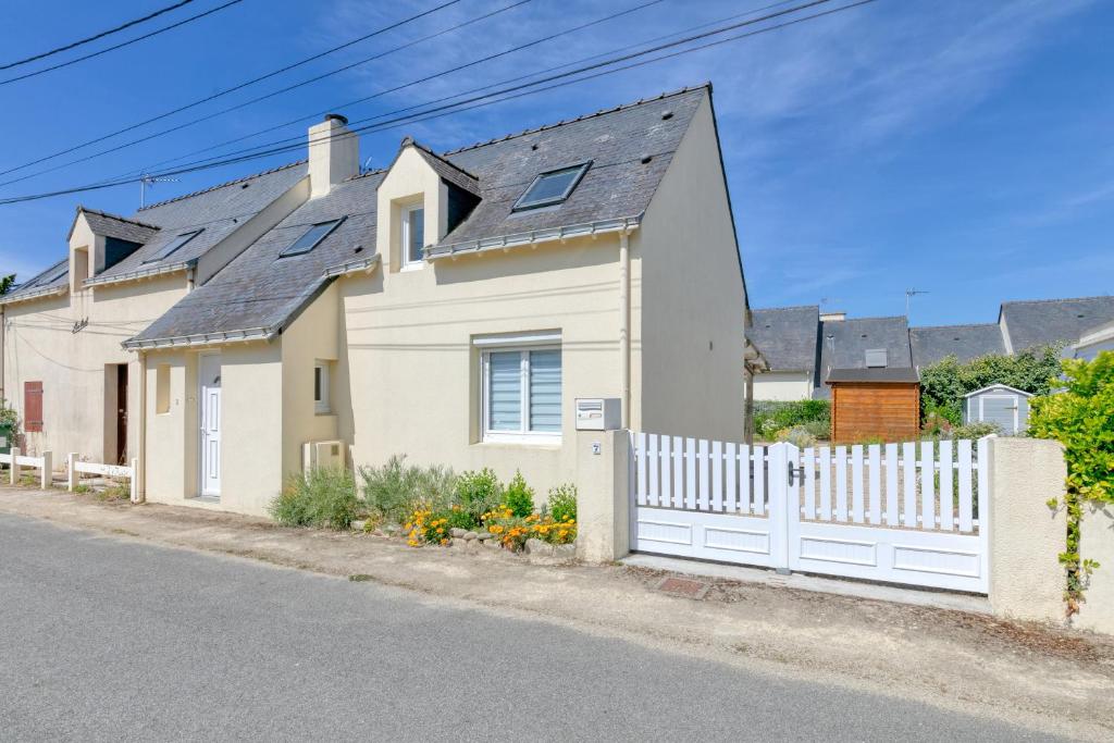 a white fence in front of a white house at Maison de vacances, 100m plage in Batz-sur-Mer